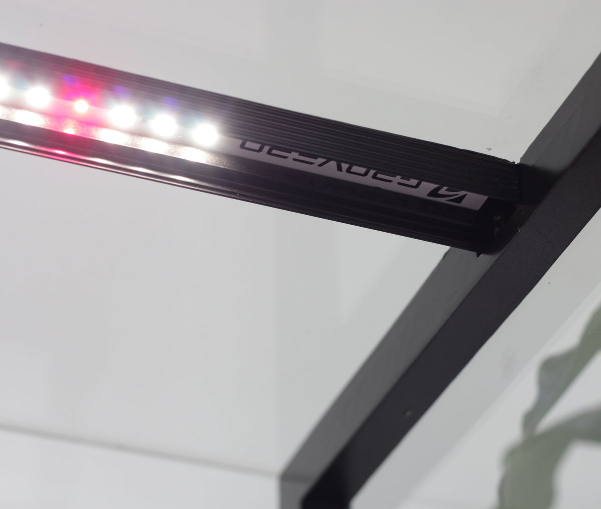 A close-up of a black LED grow light bar with illuminated red and white lights, mounted on a black metal frame against a white ceiling.