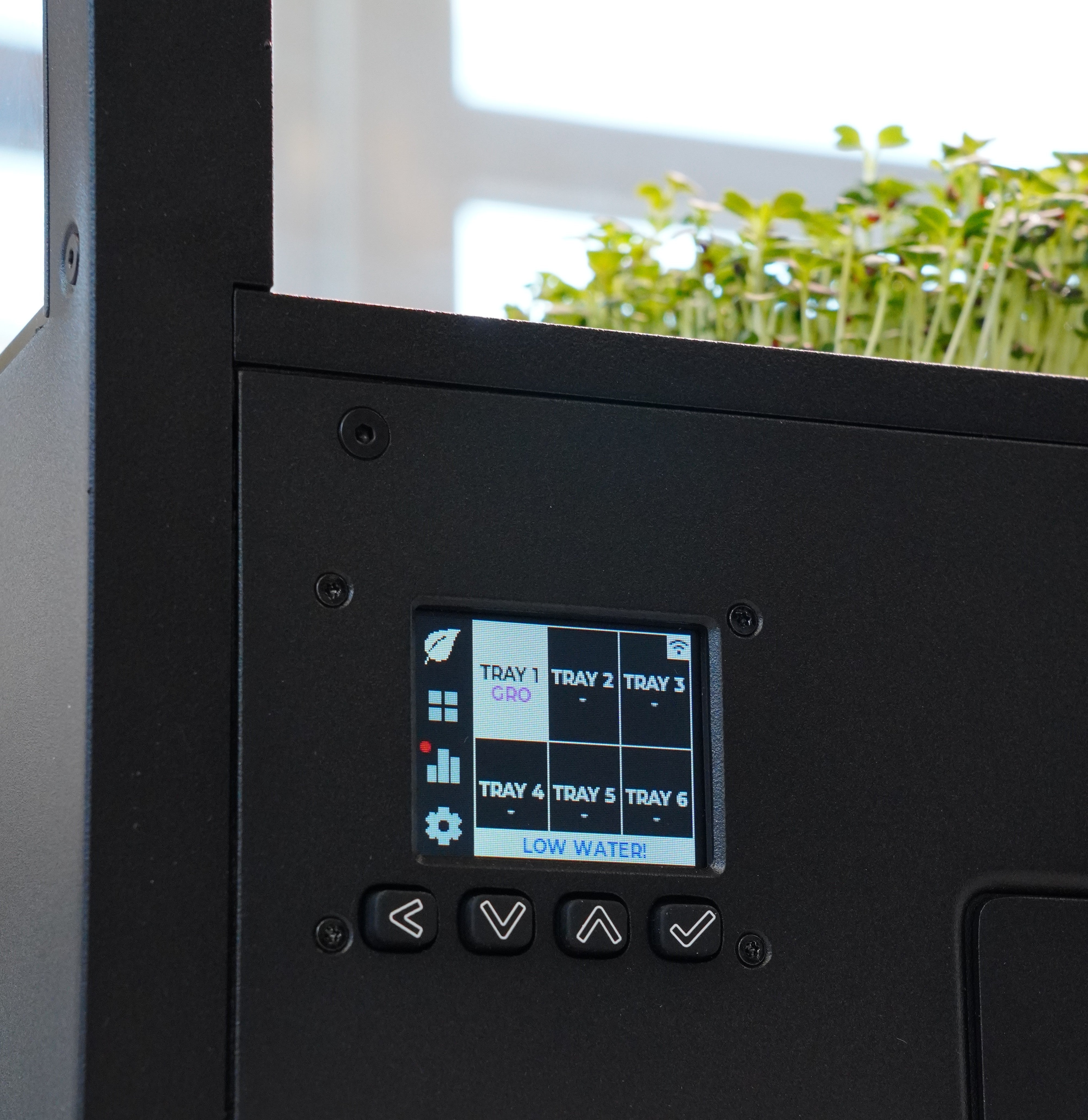 Control panel of a hydroponic system with digital display and buttons, showing plant growth stages.