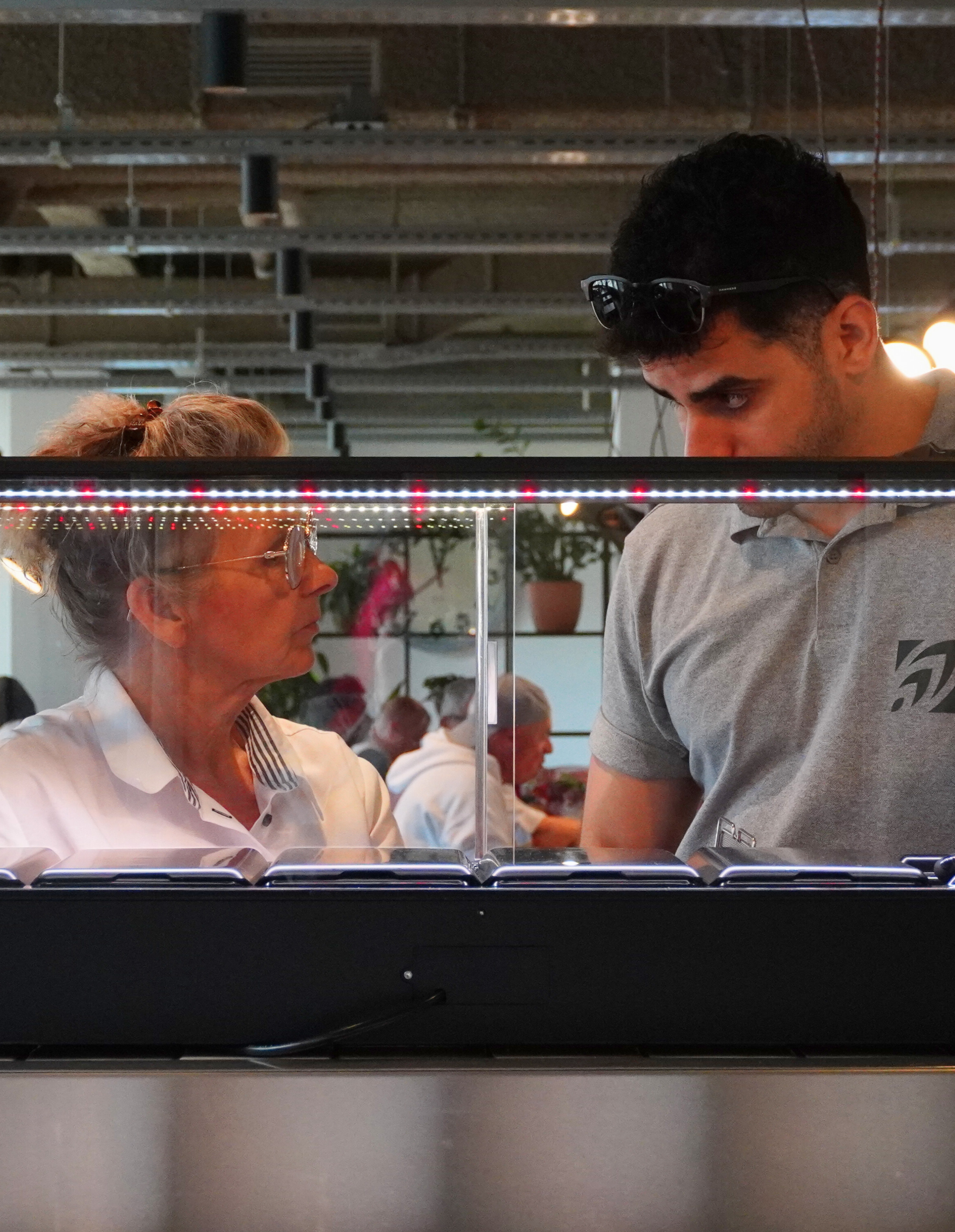 Two people looking at an indoor microfarm and people in the background.