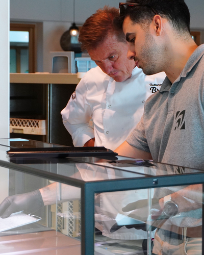 Two individuals, one in a chef's uniform, looking at an indoor microfarm in a kitchen setting.