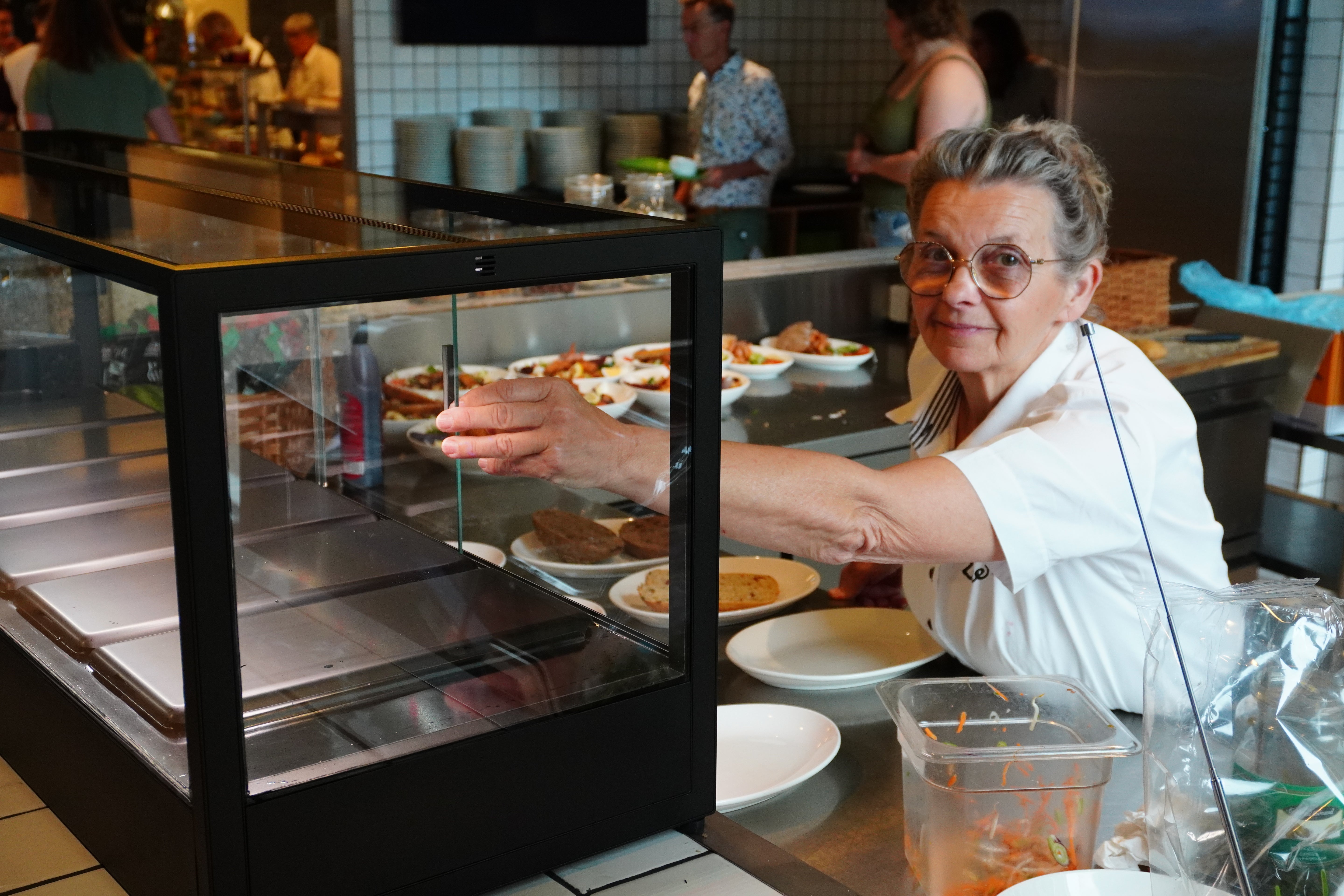 Chef interacting with indoor microfarm in a professional kitchen.
